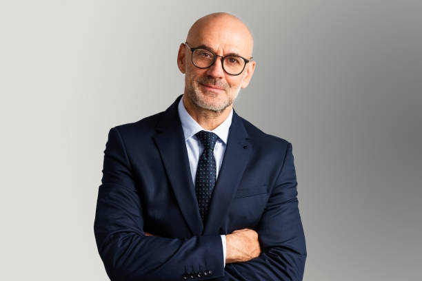 Cropped shot of executive senior businessman wearing suit and tie while standing at isolated grey background. Copy space.